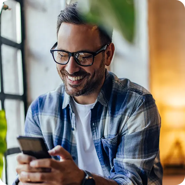 A man is laughing and looking at the smartphone