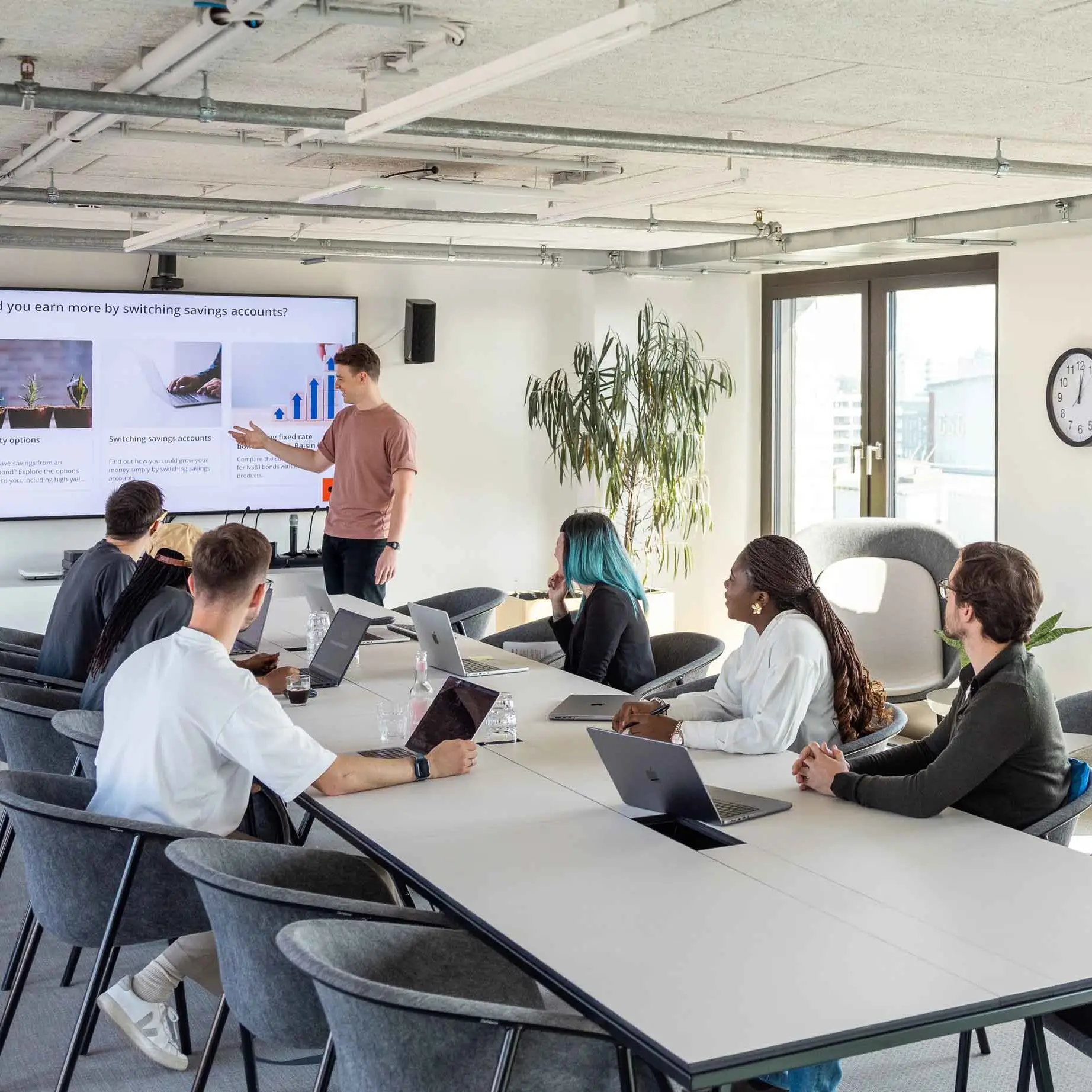 A number of colleagues are sitting in a meeting room, following a presentation held by another colleage at the board.