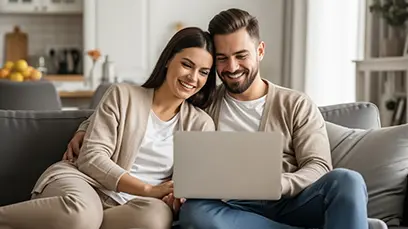 Ein Paar sitzt eng aneinander gelehnt. Beide schauen gemeinsam auf einen LapTop.